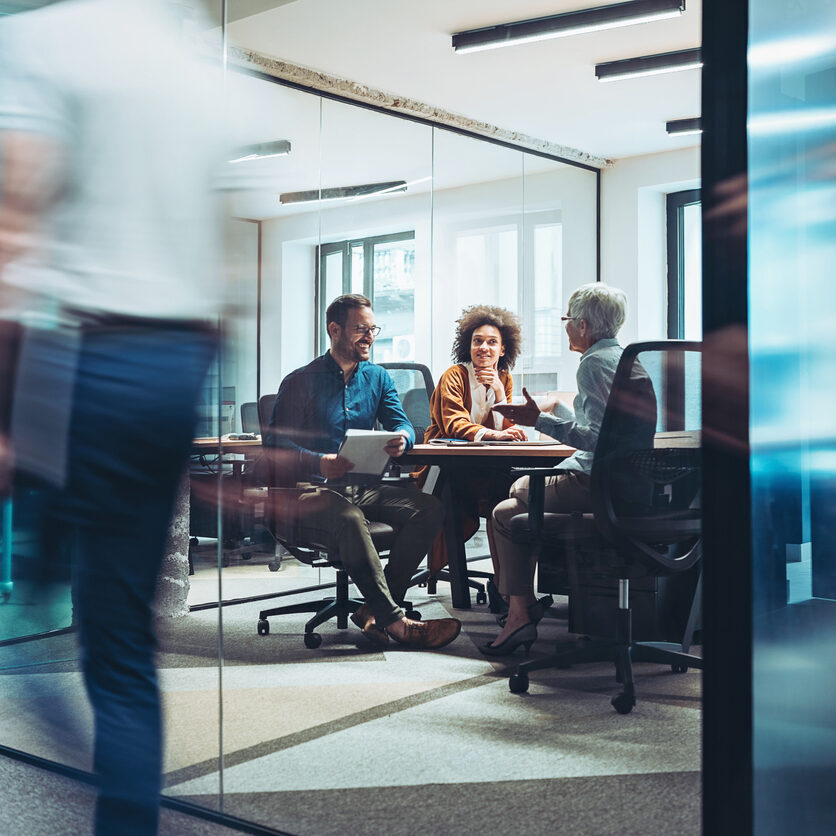 Group of B2B persons having a meeting in a closed glass conference room