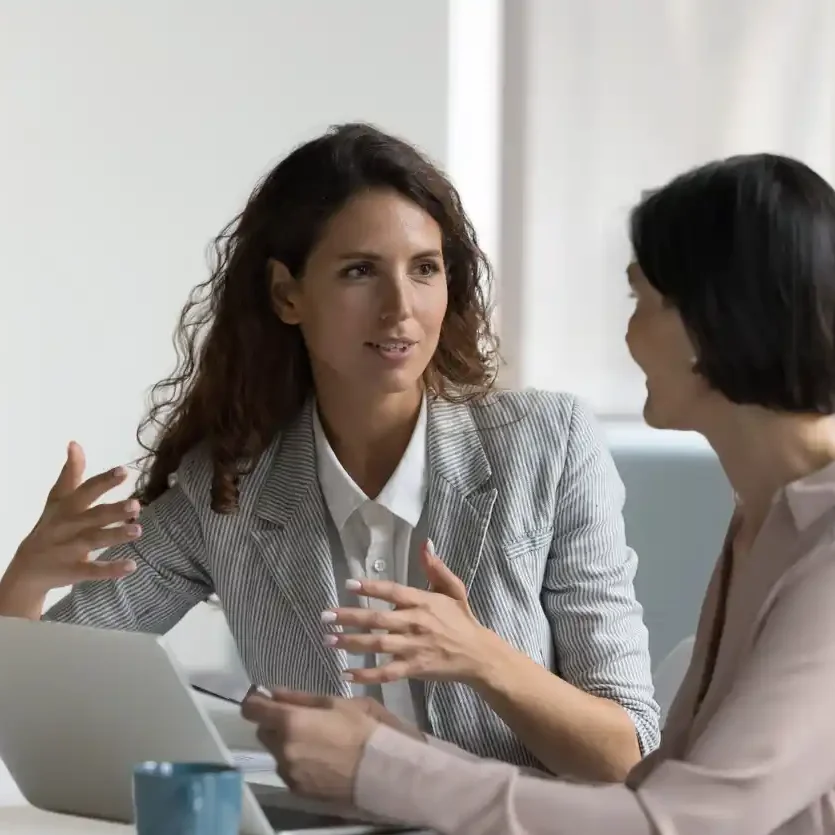 best content marketer australia.jpg SEO specialist discussing with client the importance of keyword research in office in front of open laptop and coffee mug.
