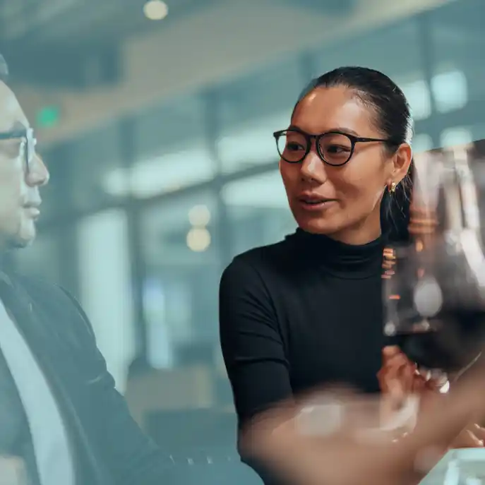 Oriental woman with glasses at a dinner table looking to colleagues. She is the only one not with a blue gradient over her.