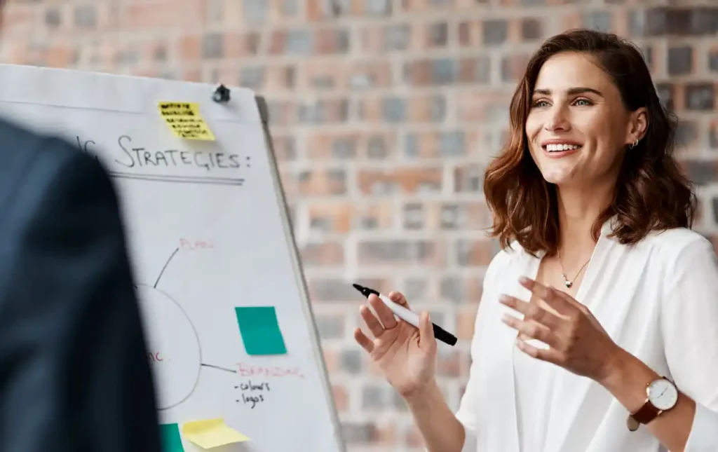 a female content marketer standing next to a white board with financial clients on the side of image