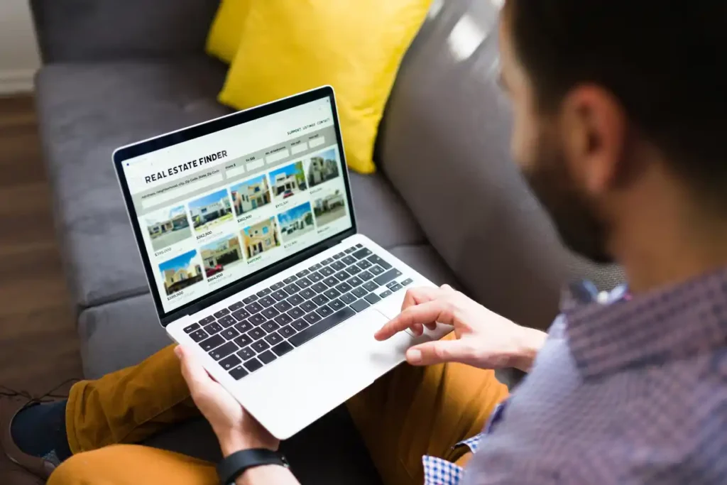 Property buyer looking at real estate listing copy on laptop computer.