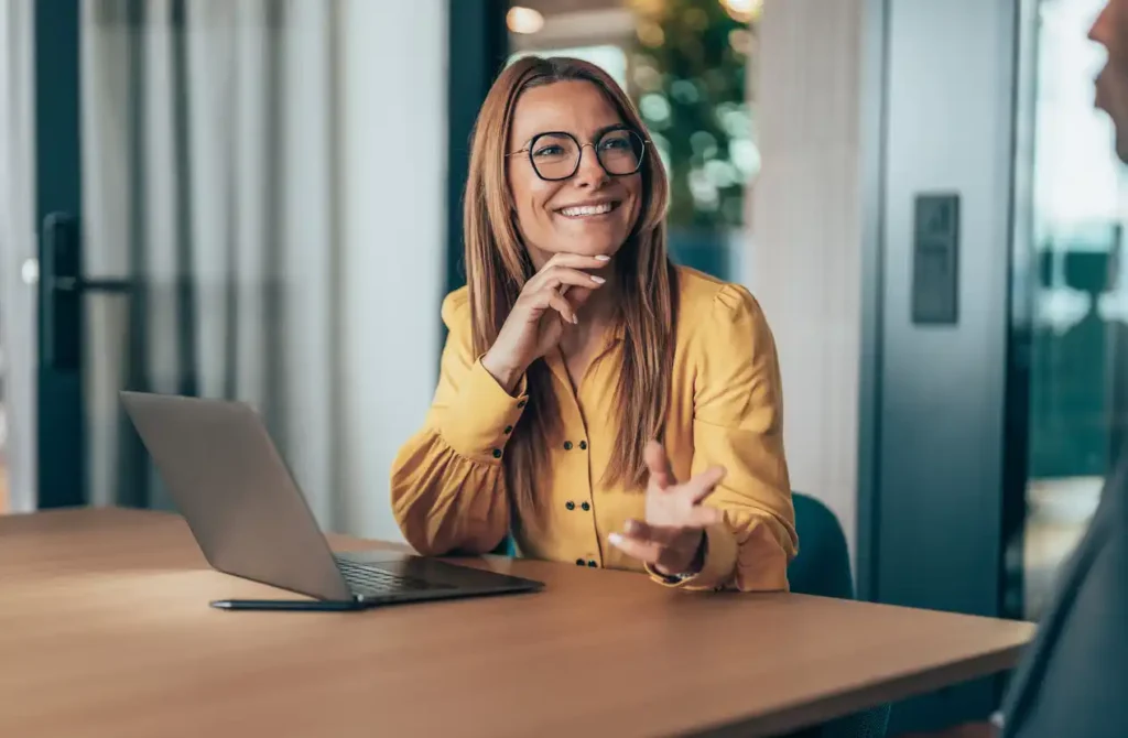 a woman sitting at a table with a laptop